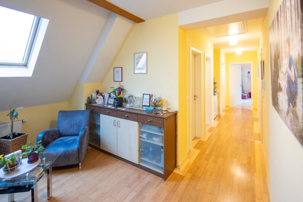 Heller Flur mit Sitzecke und Sideboard im freundlichen Wartebereich der Hebammenpraxis. Impressum